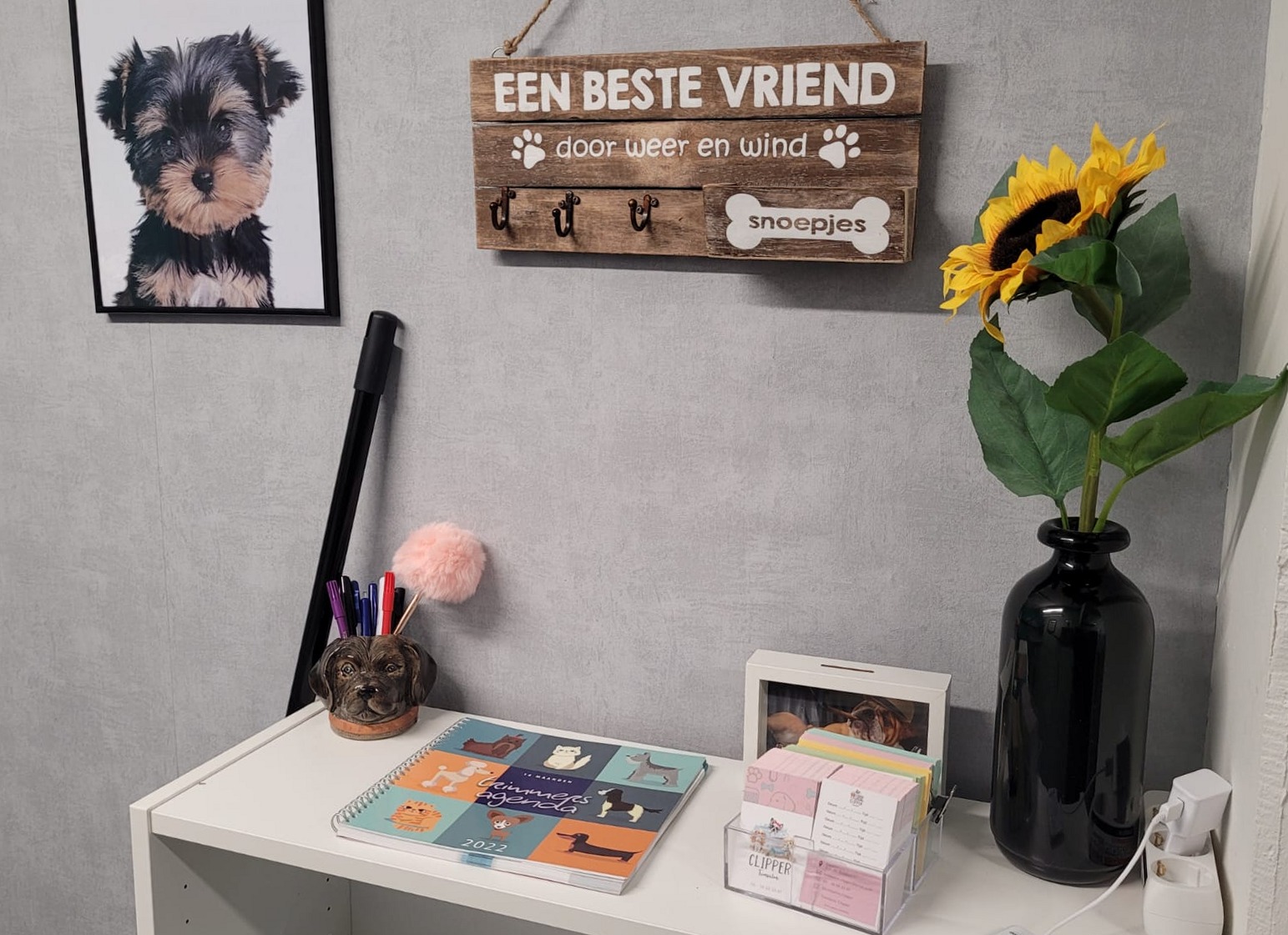 Ontvangsthoek van de salon met hondenportret en een bord over vriendschap met honden